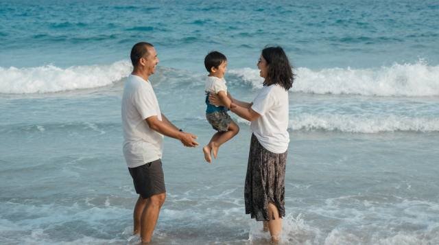 A family walking hand in hand along the shore at golden hour
